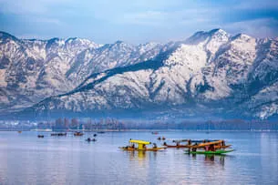 Shikara on mirror lake against snowy mountains